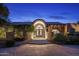 Elegant home entrance featuring arched doorway, wrought iron doors, brick facade, and manicured landscaping in the front at 8312 N Golf Dr, Paradise Valley, AZ 85253