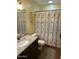Bathroom with granite countertop, dark wood cabinet, and tub-shower combination with decorative curtain at 8981 W Tuckey Ln, Glendale, AZ 85305