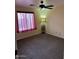Simple bedroom with neutral carpeting, a ceiling fan, and window with long, red curtains at 8981 W Tuckey Ln, Glendale, AZ 85305