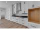 Bright kitchen with white cabinets, dark countertops, stainless steel hood, and hardwood floors at Xxx S Hunt Hwy, Queen Creek, AZ 85142