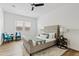 Well-lit bedroom featuring a tufted bed, wood-look floors, and seating near the window at 10134 E Talon Ave, Mesa, AZ 85212