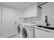 Laundry room is equipped with modern appliances, storage cabinets, and a sink at 10360 N 98Th St, Scottsdale, AZ 85258