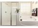 Bathroom with a glass door shower, a large soaking tub, and a window with decorative glass blocks at 10452 E Natal Ave, Mesa, AZ 85209