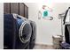 Laundry room with modern blue front-loading washer and dryer and tile floor at 10452 E Natal Ave, Mesa, AZ 85209