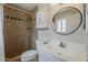 This bathroom features a tiled walk-in shower with decorative trim and a modern white vanity and round mirror at 11210 S Bannock St, Phoenix, AZ 85044