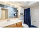 Bright bathroom featuring wood vanity, large mirror, and shower-tub combination with blue shower curtain at 1289 Leisure World --, Mesa, AZ 85206