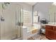 Bright bathroom featuring a glass-enclosed shower and a luxurious soaking tub beneath a window at 15910 W Shangri La Rd, Surprise, AZ 85379