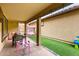 Covered back patio featuring an outdoor dining area, playful seating, and a strip of lush artificial turf at 16632 W Jenan St, Surprise, AZ 85388
