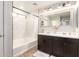 Bathroom featuring tiled shower with bathtub, double sinks, and dark wood cabinetry at 16632 W Jenan St, Surprise, AZ 85388