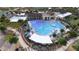Stunning aerial view of community pool with splash pad, lounge seating, and nearby clubhouse and tennis courts at 16934 W Bronco Trl, Surprise, AZ 85387