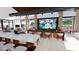 A modern lounge area with a bar, tables, and a large screen television at 16934 W Bronco Trl, Surprise, AZ 85387