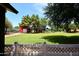 Lush backyard with lawn, red barn, and white fence, perfect for outdoor enjoyment at 17730 E Brooks Farm Rd, Gilbert, AZ 85298