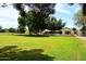 Lush backyard with mature trees, showcasing a large green lawn and the home's exterior at 17730 E Brooks Farm Rd, Gilbert, AZ 85298