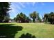 Expansive backyard with mature trees and green grass, showcasing the barn and a putting green at 17730 E Brooks Farm Rd, Gilbert, AZ 85298
