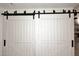 Stylish white barn doors with black hardware, provide privacy and charm at 17730 E Brooks Farm Rd, Gilbert, AZ 85298