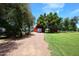 Exterior view of a large, red barn with a rolling white door, complemented by mature trees and ample space at 17730 E Brooks Farm Rd, Gilbert, AZ 85298