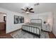 Cozy bedroom features a wrought iron bed frame, ceiling fan, and wood-look floors at 17730 E Brooks Farm Rd, Gilbert, AZ 85298
