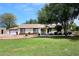 Charming single-story home with green lawn, mature trees, and neutral toned facade at 17730 E Brooks Farm Rd, Gilbert, AZ 85298