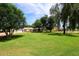 Spacious front yard with lush green lawn and mature trees, enhancing curb appeal at 17730 E Brooks Farm Rd, Gilbert, AZ 85298