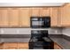 Well-equipped kitchen with light wood cabinets, dark countertops, and modern black appliances at 20100 N 78Th N Pl # 3212, Scottsdale, AZ 85255