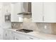 Close-up of a kitchen featuring a gas cooktop, stainless steel vent hood, white cabinets, and tile backsplash at 20606 E Avenida Del Valle Ct, Queen Creek, AZ 85142