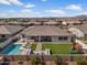 An aerial view showcases a backyard including a pool, artificial grass, playground set, and cozy lounge area at 22991 E Via De Olivos --, Queen Creek, AZ 85142
