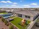 An aerial view of the backyard showcases a pool, artificial grass, playground set, and cozy lounge area at 22991 E Via De Olivos --, Queen Creek, AZ 85142