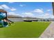 Expansive backyard with artificial grass, a play structure, and a pool in the distance at 22991 E Via De Olivos --, Queen Creek, AZ 85142
