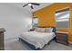 Bright bedroom with a yellow accent wall, white bedding, neutral carpet and ceiling fan at 22991 E Via De Olivos --, Queen Creek, AZ 85142