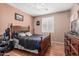 Comfortable bedroom featuring a wood frame bed with stylish dark bedding and wood flooring at 26249 N 68Th Ln, Peoria, AZ 85383