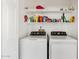 Clean laundry room featuring white front-load washer and dryer with overhead shelving at 2650 W Union Hills Dr # 100, Phoenix, AZ 85027