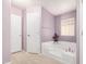 Bathroom with lilac walls featuring a tub, glass block window and a white door at 33852 N 52Nd St, Cave Creek, AZ 85331