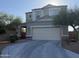 Two-story home featuring a two-car garage and a covered porch with stone accents. Landscaped with desert trees and bushes at 3402 N 300Th Dr, Buckeye, AZ 85396
