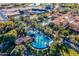 Expansive aerial view showcasing a resort-style pool with lounge areas, mature trees, and surrounding buildings at 36298 N Crucillo Dr, Queen Creek, AZ 85140