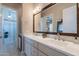 Elegant bathroom featuring double sinks, granite counters, tile flooring, and a large framed mirror at 36298 N Crucillo Dr, Queen Creek, AZ 85140