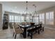 Bright dining room features large table with seating, modern chandeliers, and natural light from shuttered windows at 36298 N Crucillo Dr, Queen Creek, AZ 85140