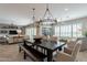 Open concept dining area boasts a large wooden table with bench seating and stylish chandeliers at 36298 N Crucillo Dr, Queen Creek, AZ 85140