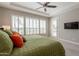 Sun-drenched main bedroom boasting plantation shutters, television, and tray ceiling at 36298 N Crucillo Dr, Queen Creek, AZ 85140