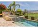 Outdoor kitchen with built-in grill, lush trees, a golf course view, and blooming red flowers at 36298 N Crucillo Dr, Queen Creek, AZ 85140
