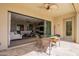 Covered patio with open sliding doors overlooks the bright living room, lush golf course views beyond at 36298 N Crucillo Dr, Queen Creek, AZ 85140