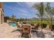 Inviting patio with cushioned chairs, blue fire pit, pool, and green golf course views in background at 36298 N Crucillo Dr, Queen Creek, AZ 85140