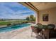 Inviting covered patio with dining set overlooks a pool with water feature and lush golf course views at 36298 N Crucillo Dr, Queen Creek, AZ 85140
