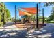 Community playground featuring shade sails, slides, climbing structures, and a nearby bench, surrounded by greenery at 36298 N Crucillo Dr, Queen Creek, AZ 85140