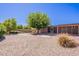 Private backyard with a large shade tree, neutral rock landscaping and a covered patio at 3823 E Poinsettia Dr, Phoenix, AZ 85028