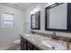 Bathroom featuring double sinks, granite countertops, and modern fixtures and mirrors at 3823 E Poinsettia Dr, Phoenix, AZ 85028