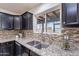 Close up on kitchen sink with granite countertops, tile backsplash, and window view to the backyard at 3823 E Poinsettia Dr, Phoenix, AZ 85028