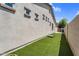 Side yard featuring artificial grass and stucco wall with inset windows on a sunny day at 3872 E Jude Ln, Gilbert, AZ 85298
