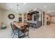 Well-lit dining space near a custom bar, featuring an oversized hardwood table and decor at 40725 W Hall Dr, Maricopa, AZ 85138