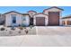 Home exterior featuring a three-car garage, desert landscaping, and a well-maintained facade at 40725 W Hall Dr, Maricopa, AZ 85138