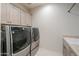 Spacious laundry room with high-end washer and dryer, and ample cabinet space at 40725 W Hall Dr, Maricopa, AZ 85138